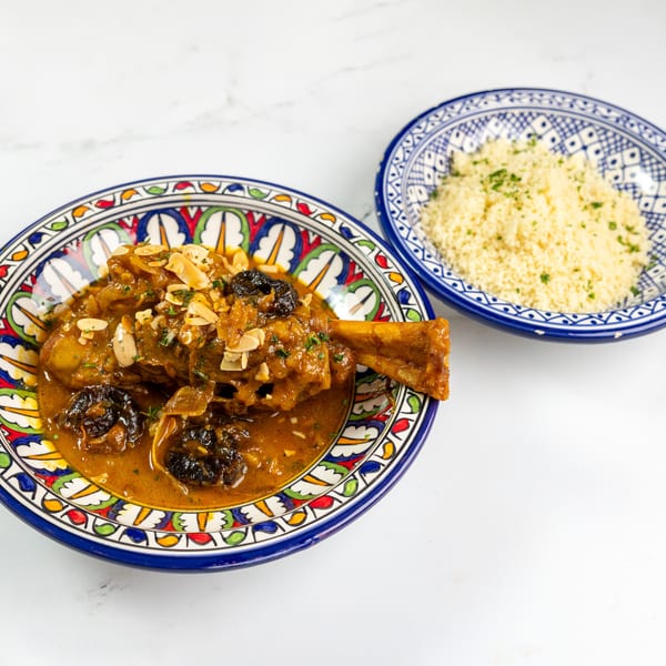 Moroccan lamb tagine with prunes and almonds, served with couscous in decorative bowls.