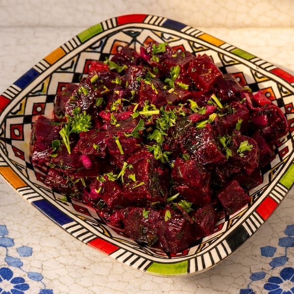 Beetroot salad with fresh parsley in a colorful, patterned bowl on a white and blue tiled surface.