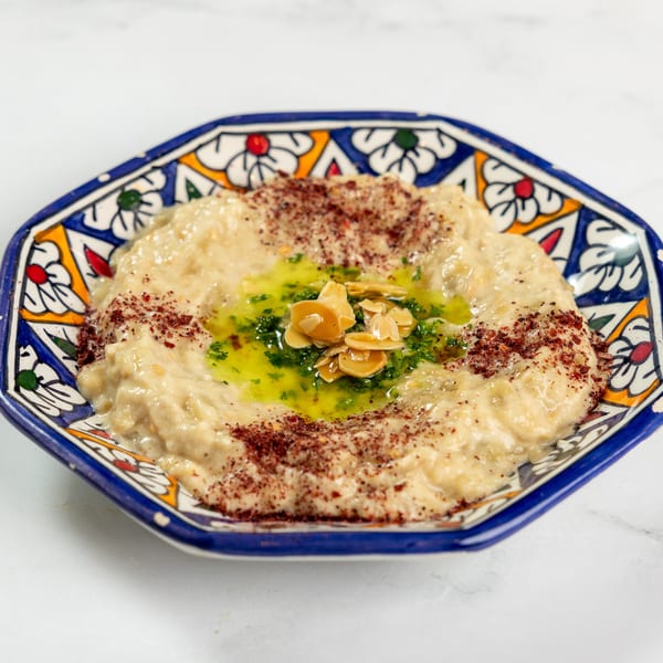 Baba Ghanoush in a decorative blue and white bowl, garnished with olive oil, parsley, and almonds.